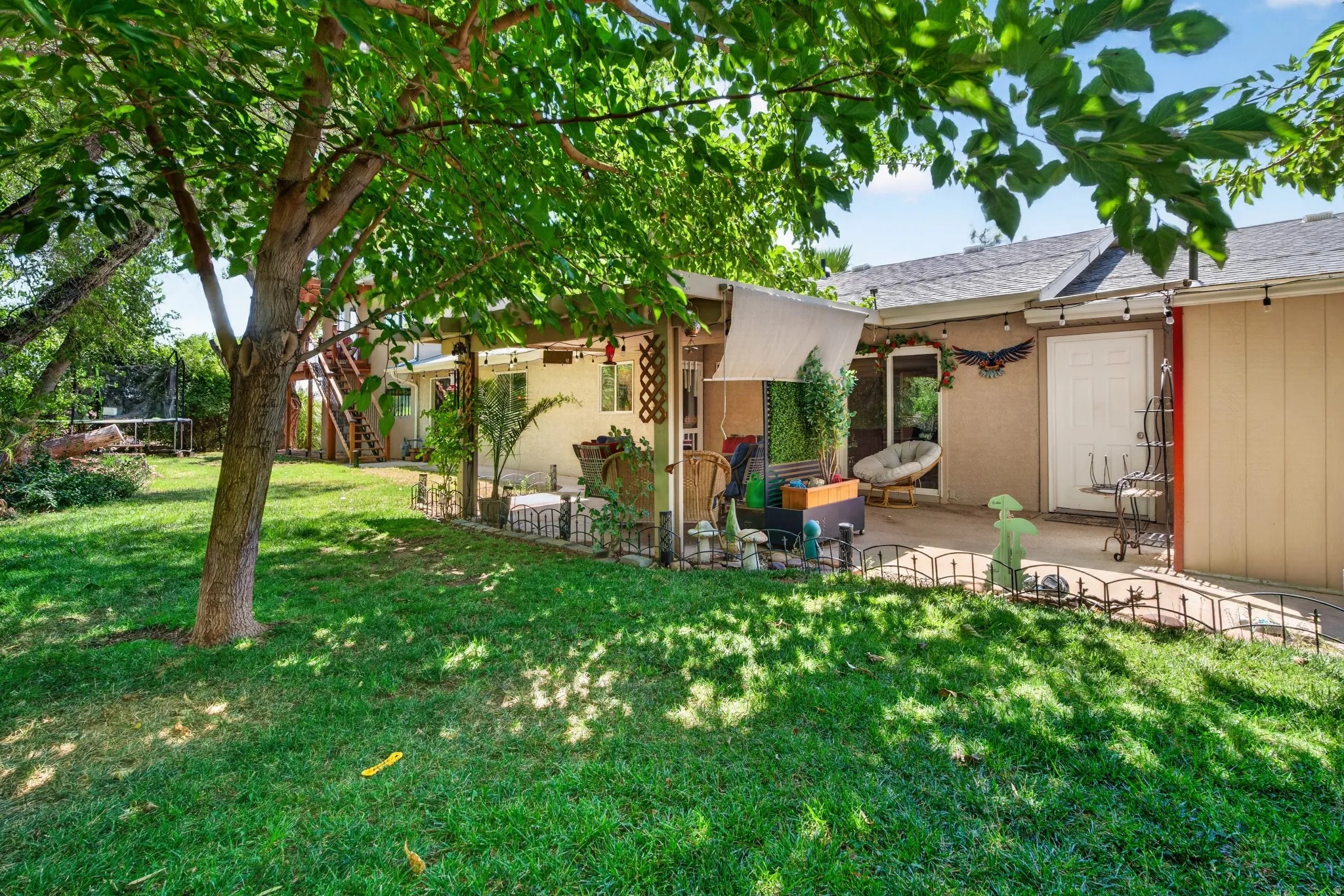 Expansive backyard with a manicured lawn, mature trees, and a concrete patio
