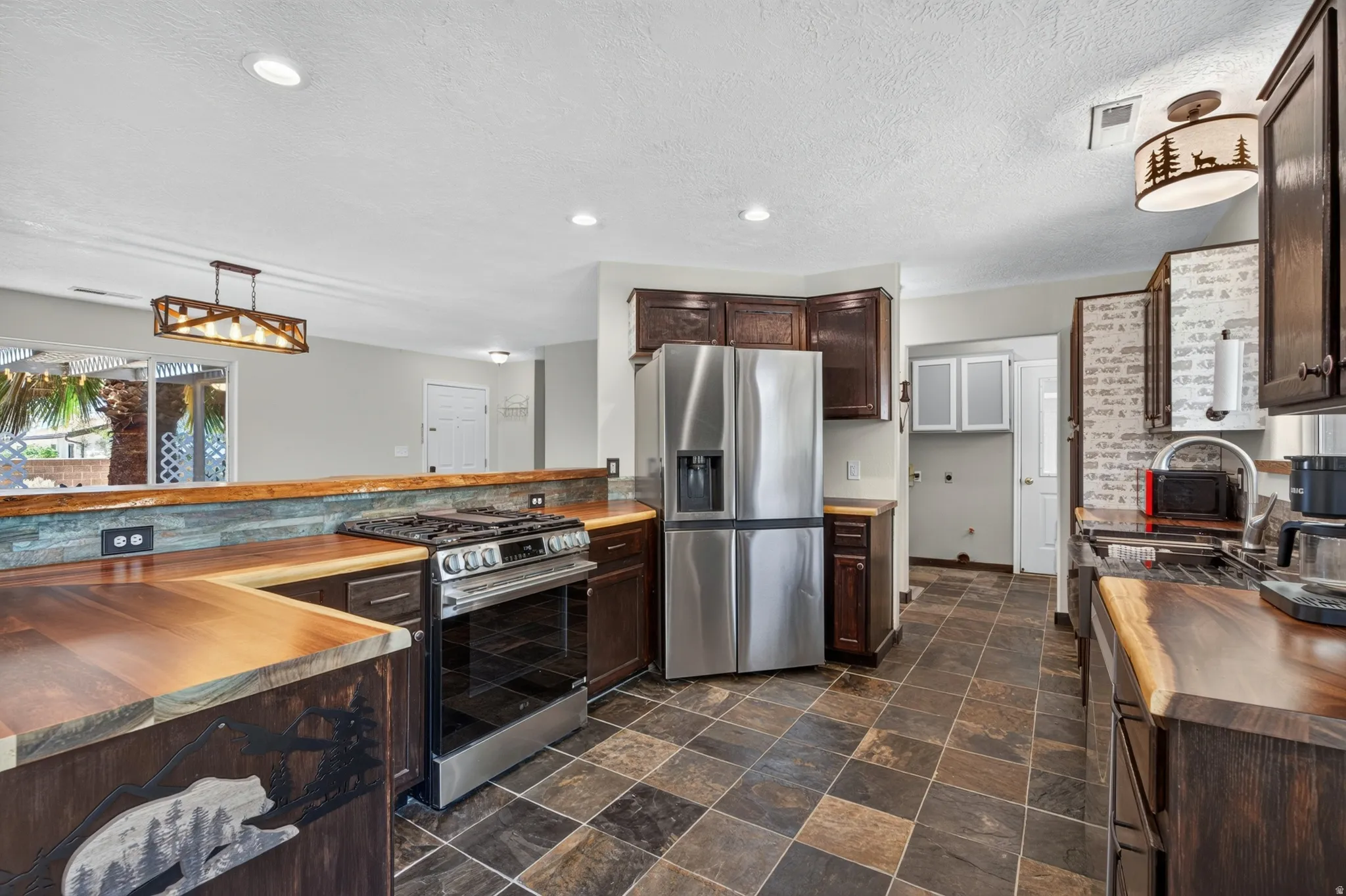 Kitchen featuring stainless steel appliances, dark wood cabinetry, and butcher block countertops