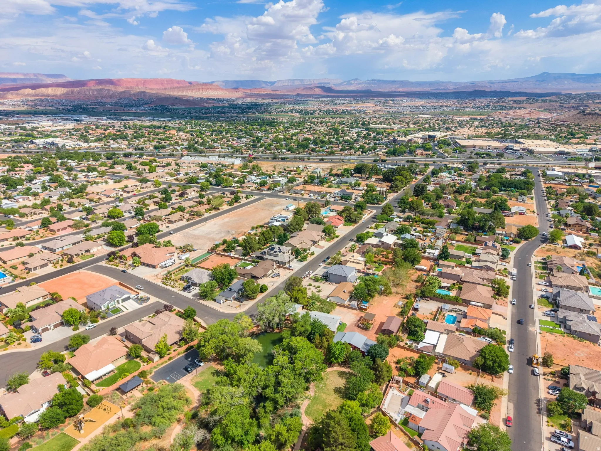 Expansive aerial view showcasing a residential neighborhood with a variety of single-story homes, mature landscaping, and paved streets
