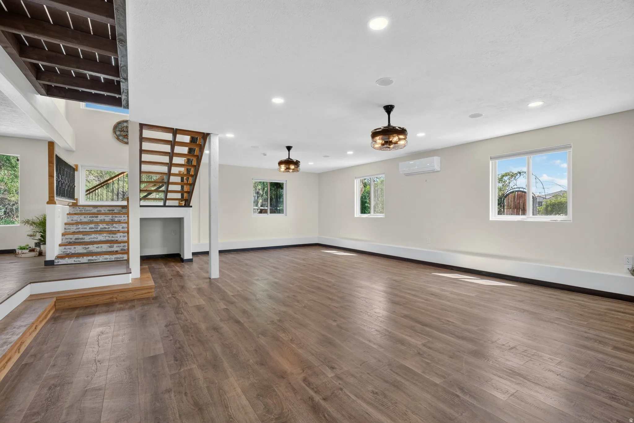 Spacious open-concept room featuring wood-finish flooring, recessed lighting, and a modern ceiling fan