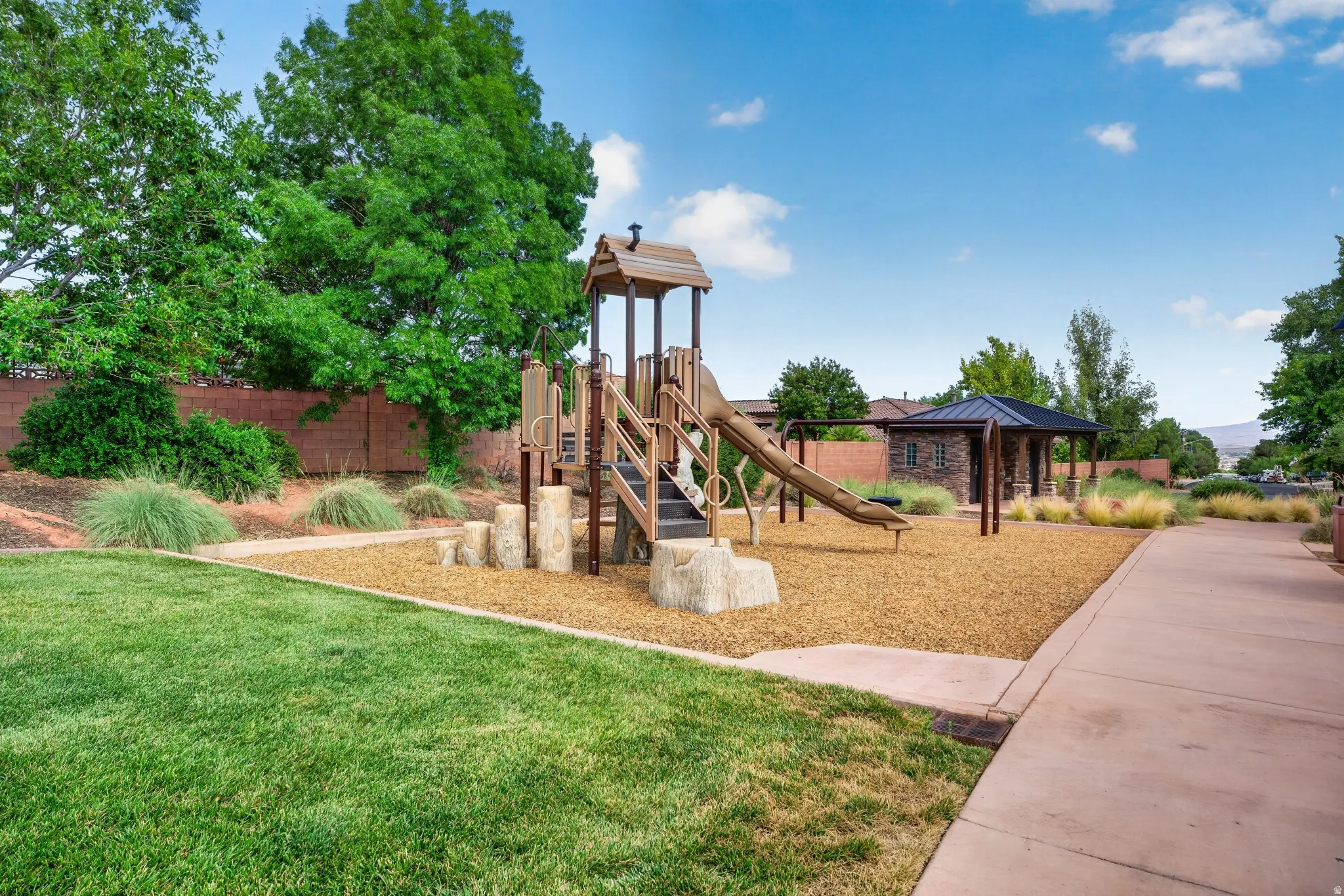 Community playground featuring a multi-level play structure with slides and climbing elements, set on a wood chip surface