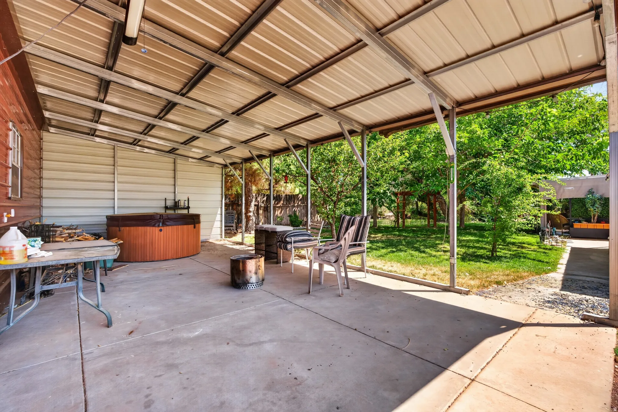 Covered concrete patio featuring a built-in hot tub, providing a sheltered outdoor space