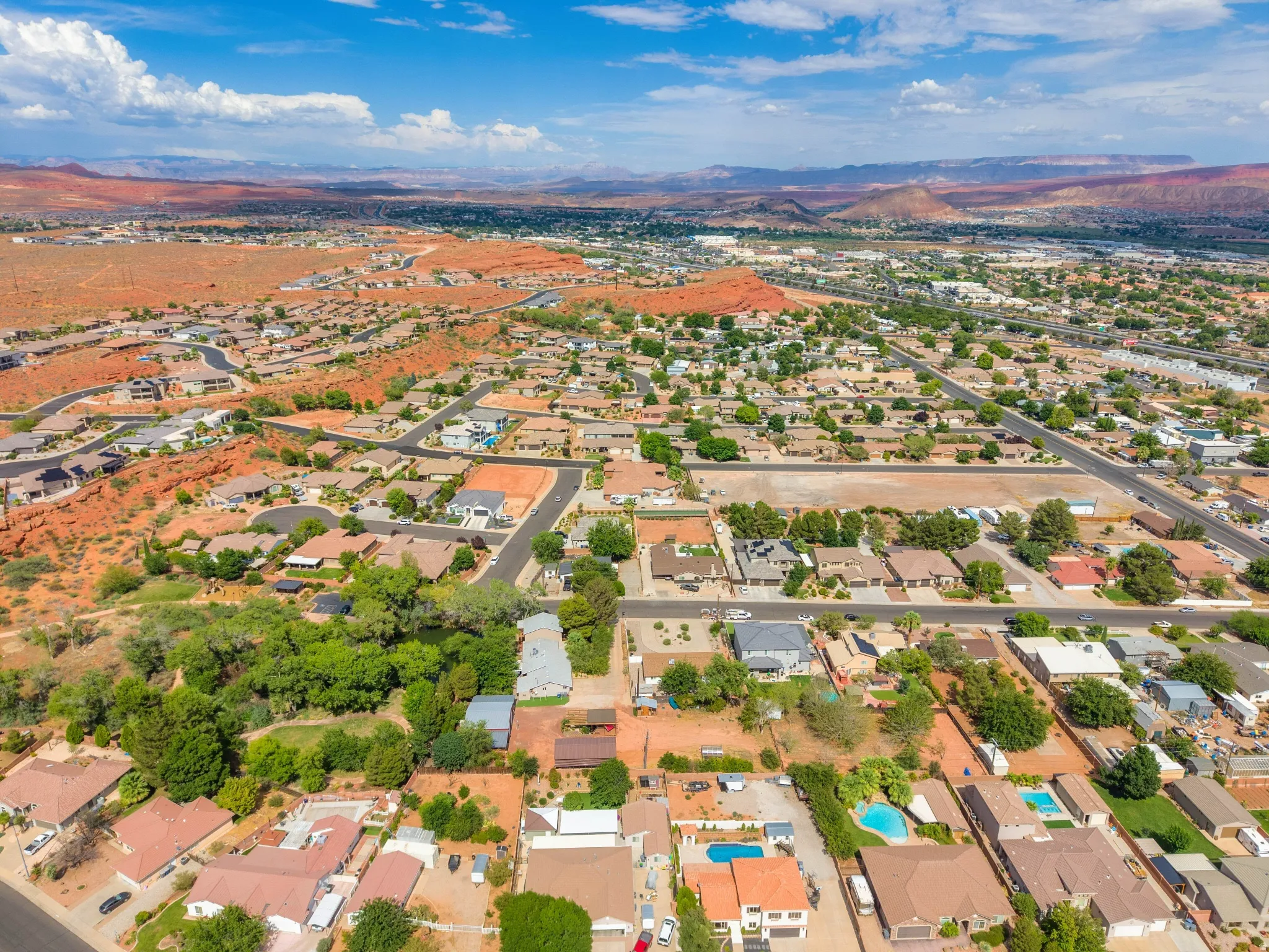 Expansive aerial perspective showcasing a residential community with red rock mountainous terrain