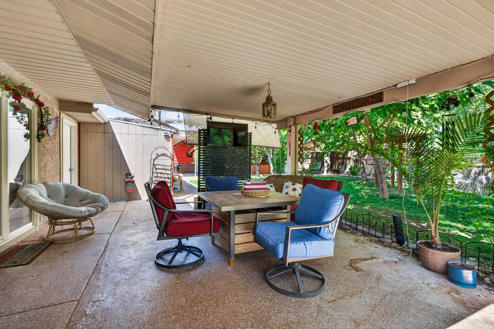 Covered patio featuring an exposed aggregate concrete surface, a slatted ceiling, and an exterior wall with a textured finish