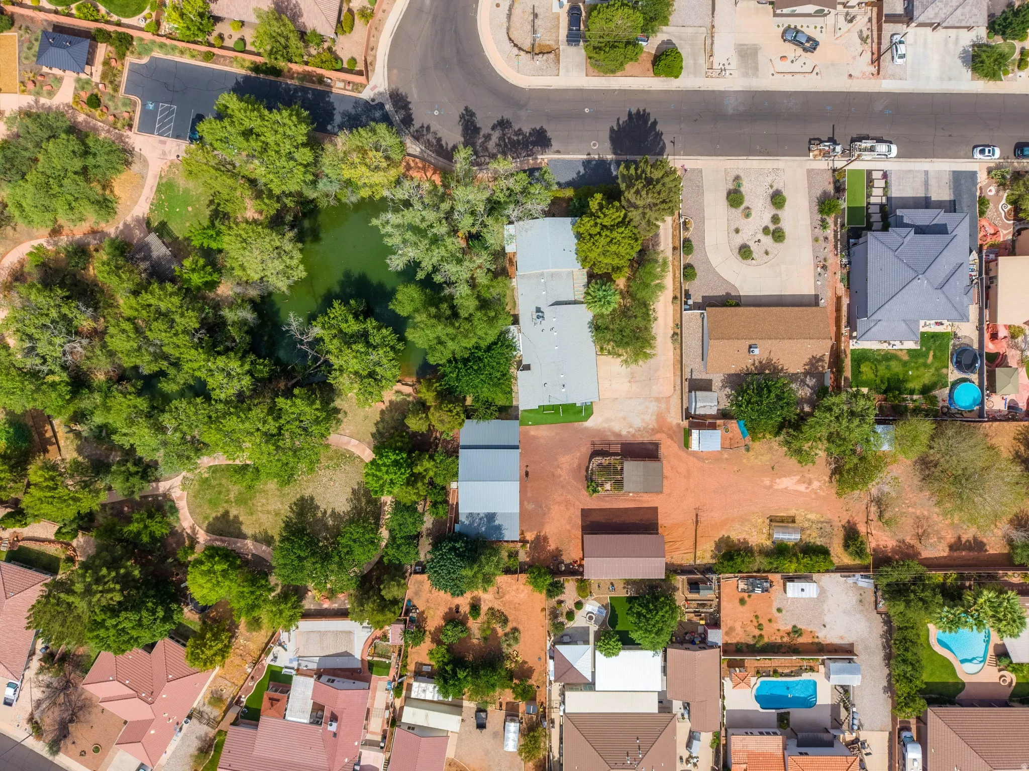 Extensive property featuring a large natural pond, mature trees, open green spaces, multiple outbuildings, and direct street access
