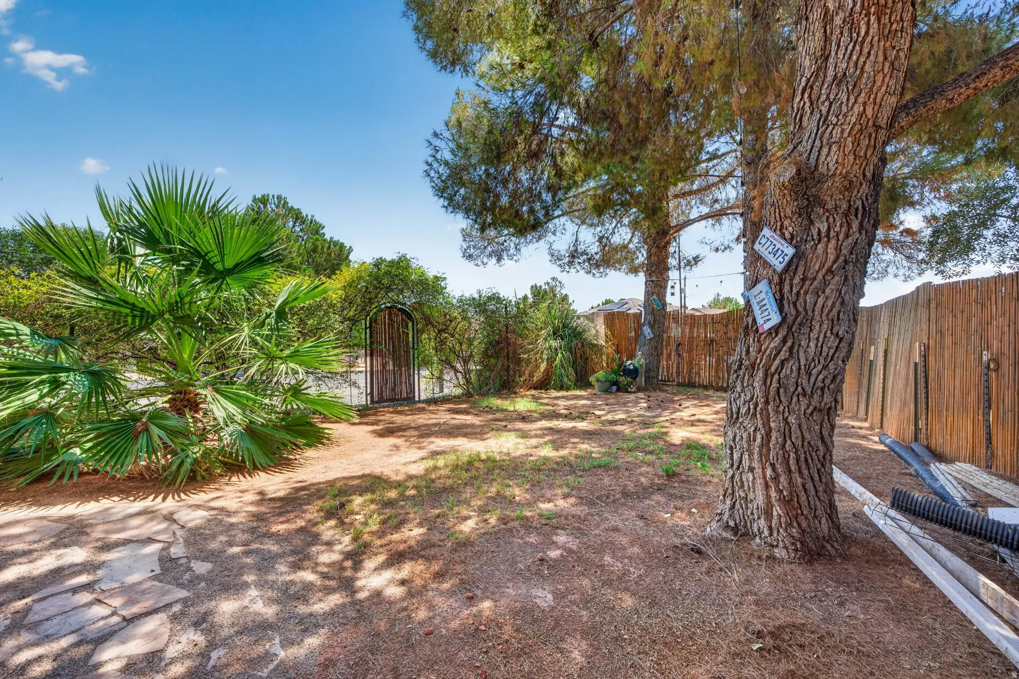 Spacious backyard featuring mature trees, a decorative wood gate, and a natural wood-slat fence