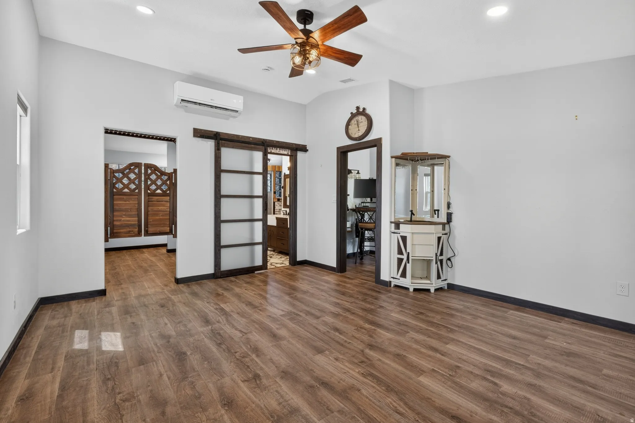 Spacious interior featuring wood-finish flooring, a ceiling fan with integrated lighting, and recessed ceiling lights