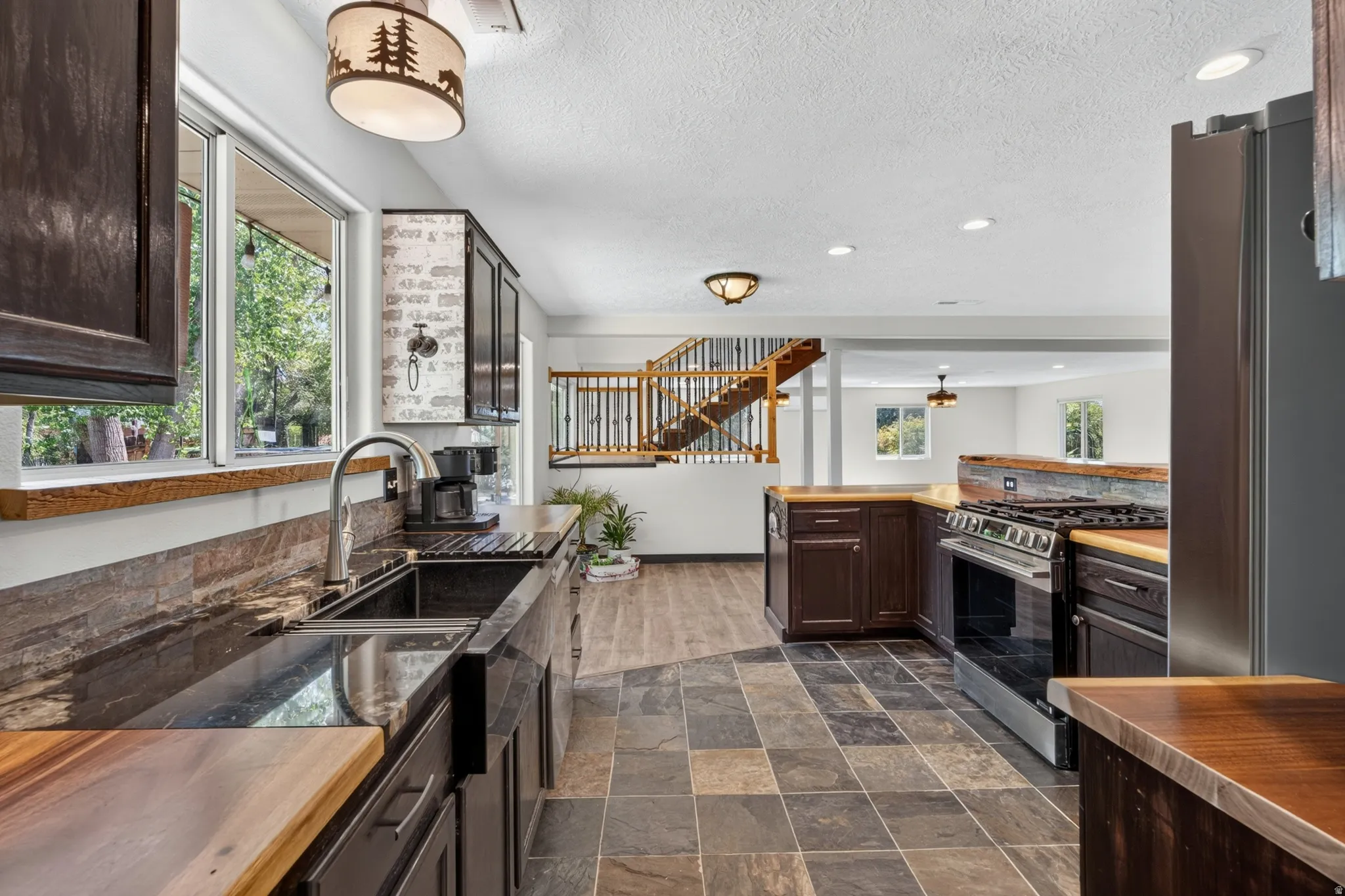 Kitchen featuring dark wood-finish cabinetry, a stone tile backsplash, and wood-finish countertops