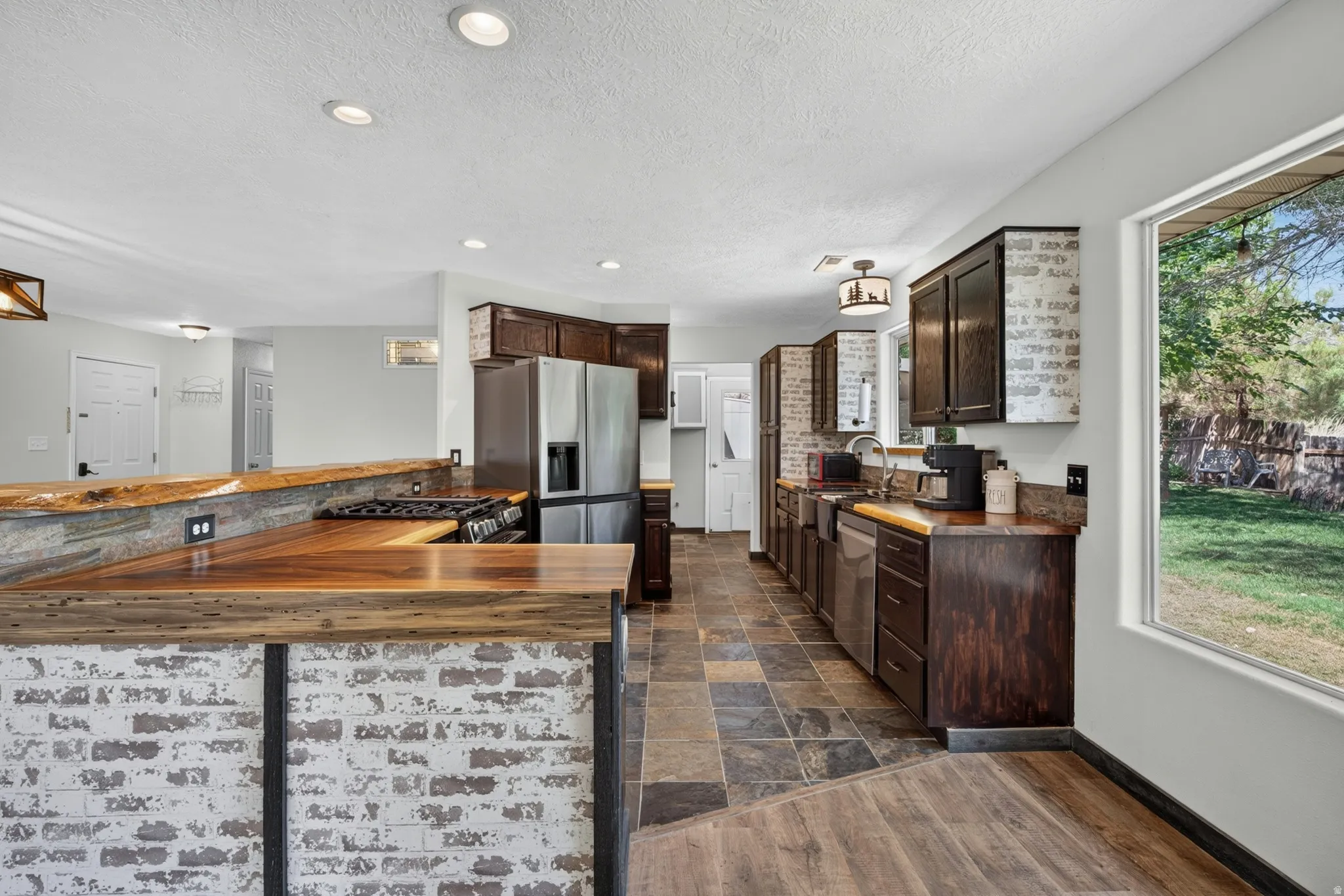 Kitchen featuring wood-finish countertops, dark cabinetry, and integrated stainless steel appliances