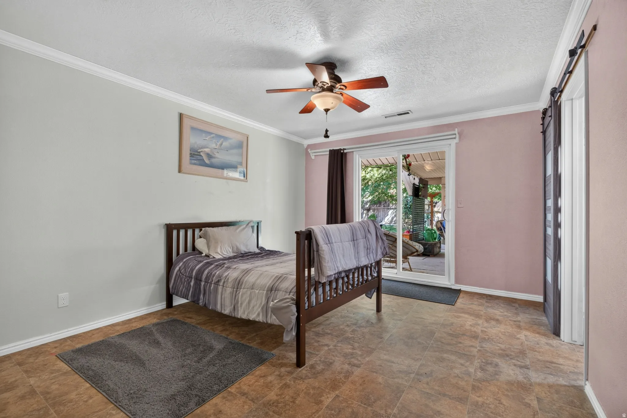 Spacious room featuring tile flooring, a ceiling fan, and crown molding