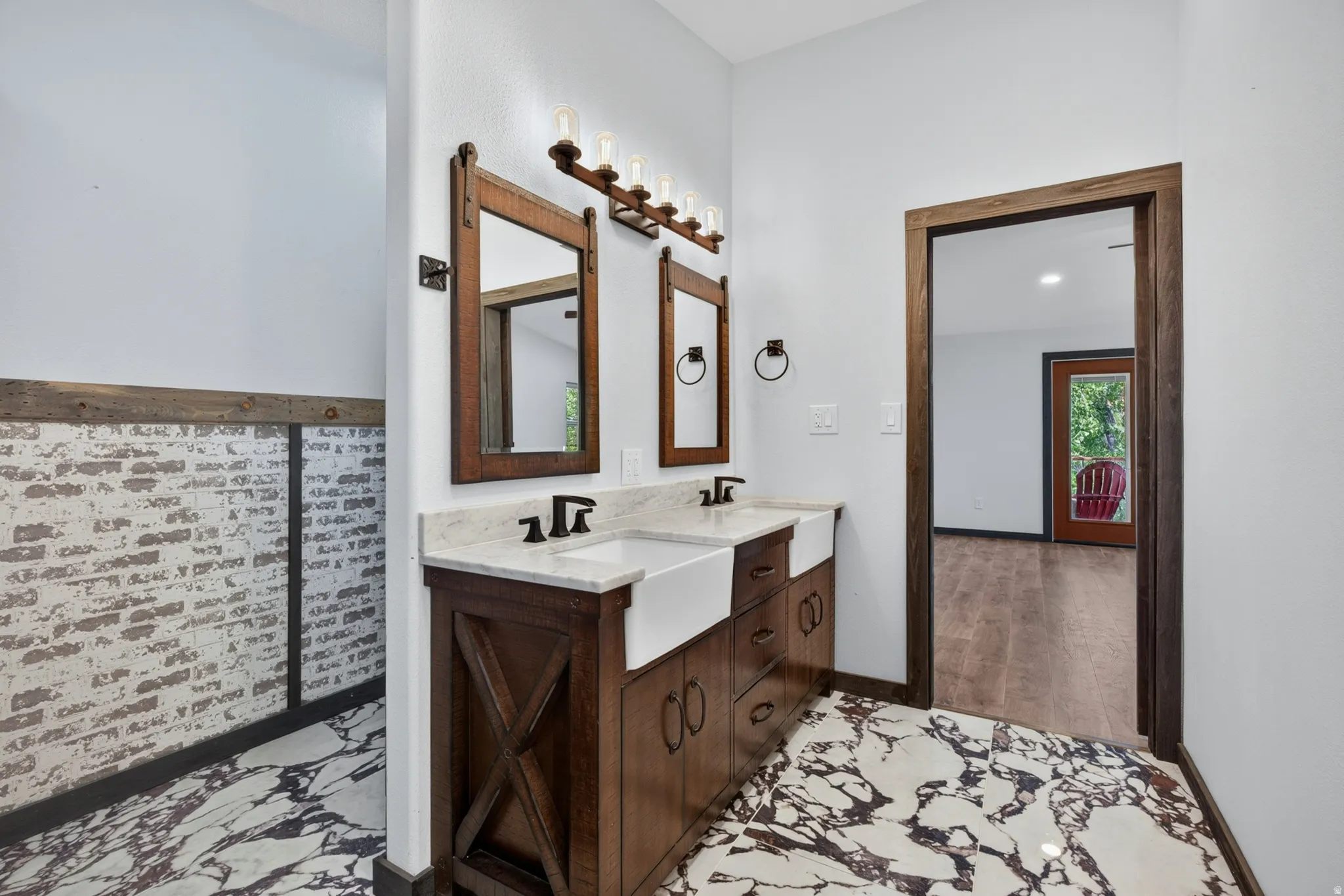 Double vanity with barn door-style mirrors, integrated farmhouse sinks, matte black fixtures, and a light-toned countertop