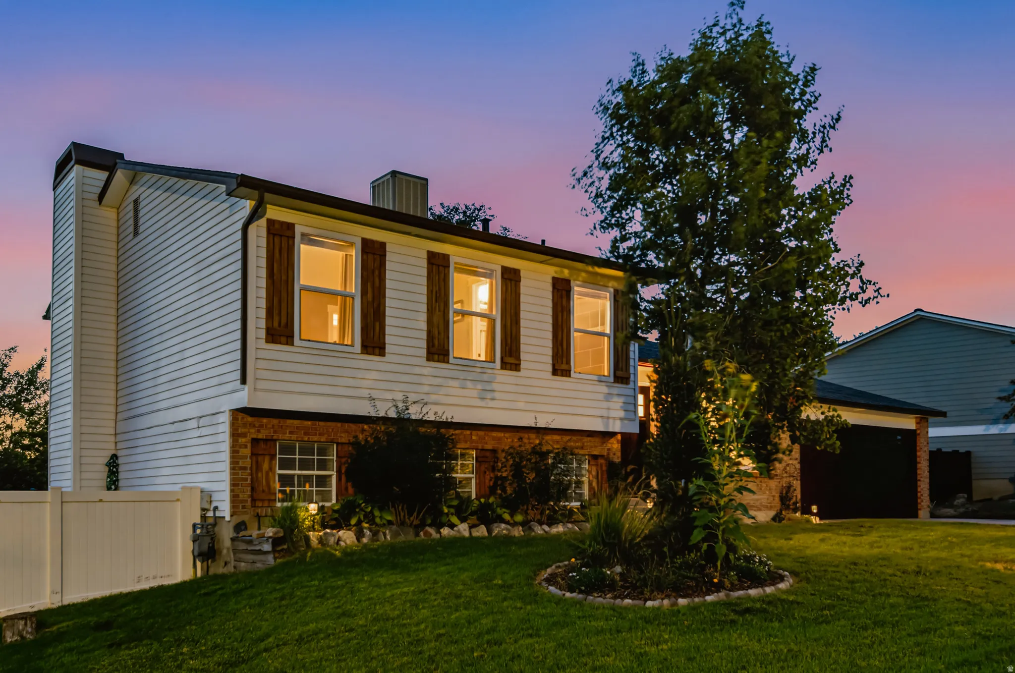 Split-level exterior featuring white siding and brick accents