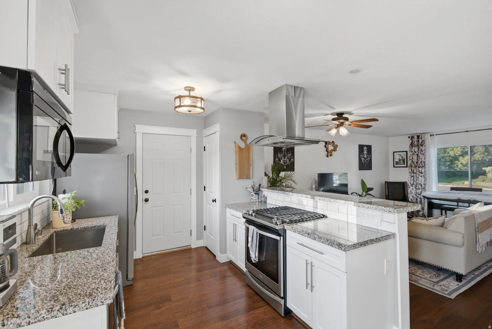 Kitchen featuring white cabinetry, granite countertops, stainless steel appliances, wood-finish flooring, and a subway tile backsplash