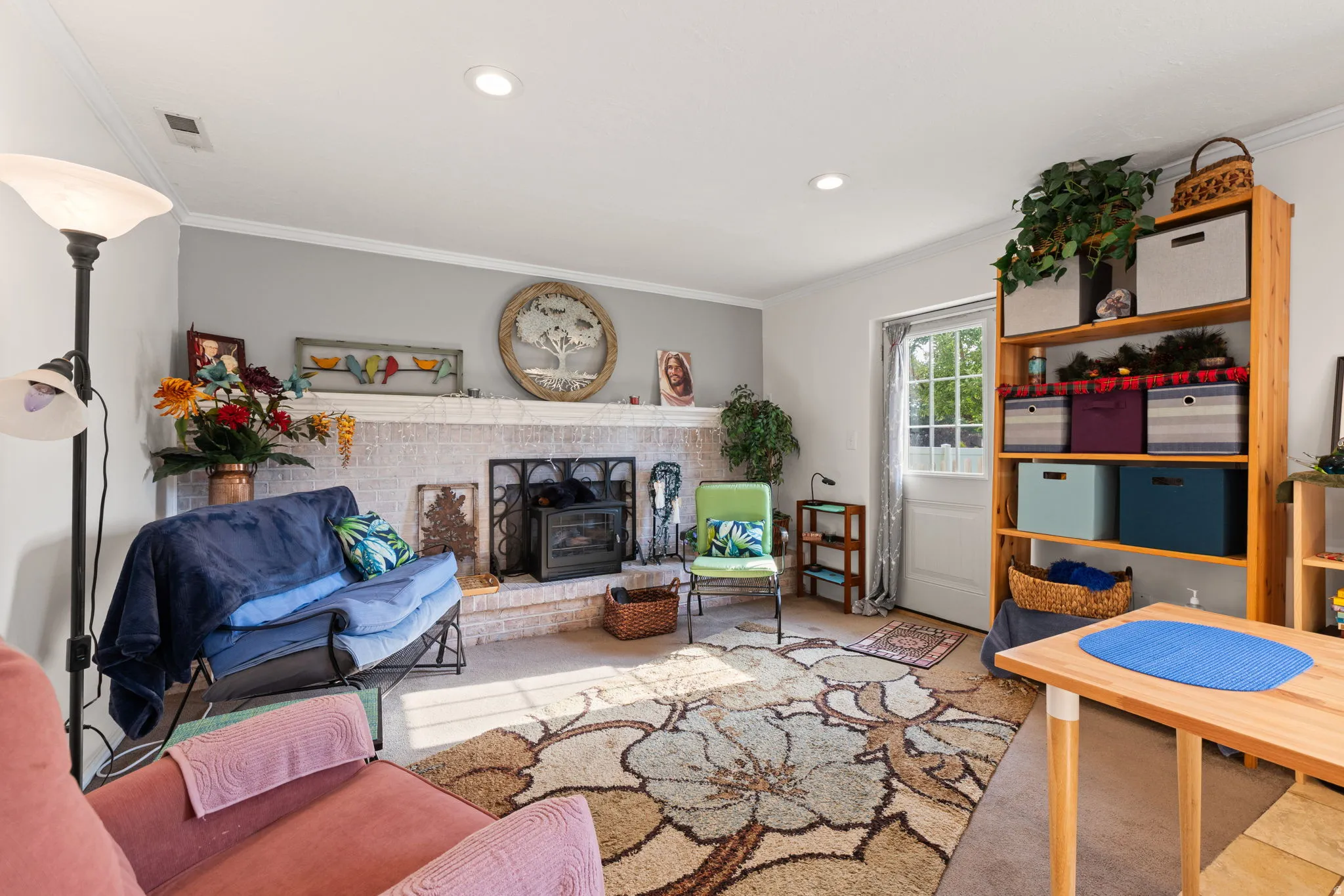 Living area featuring a white-painted brick fireplace with a dark metal firebox insert, recessed ceiling lighting, and crown molding