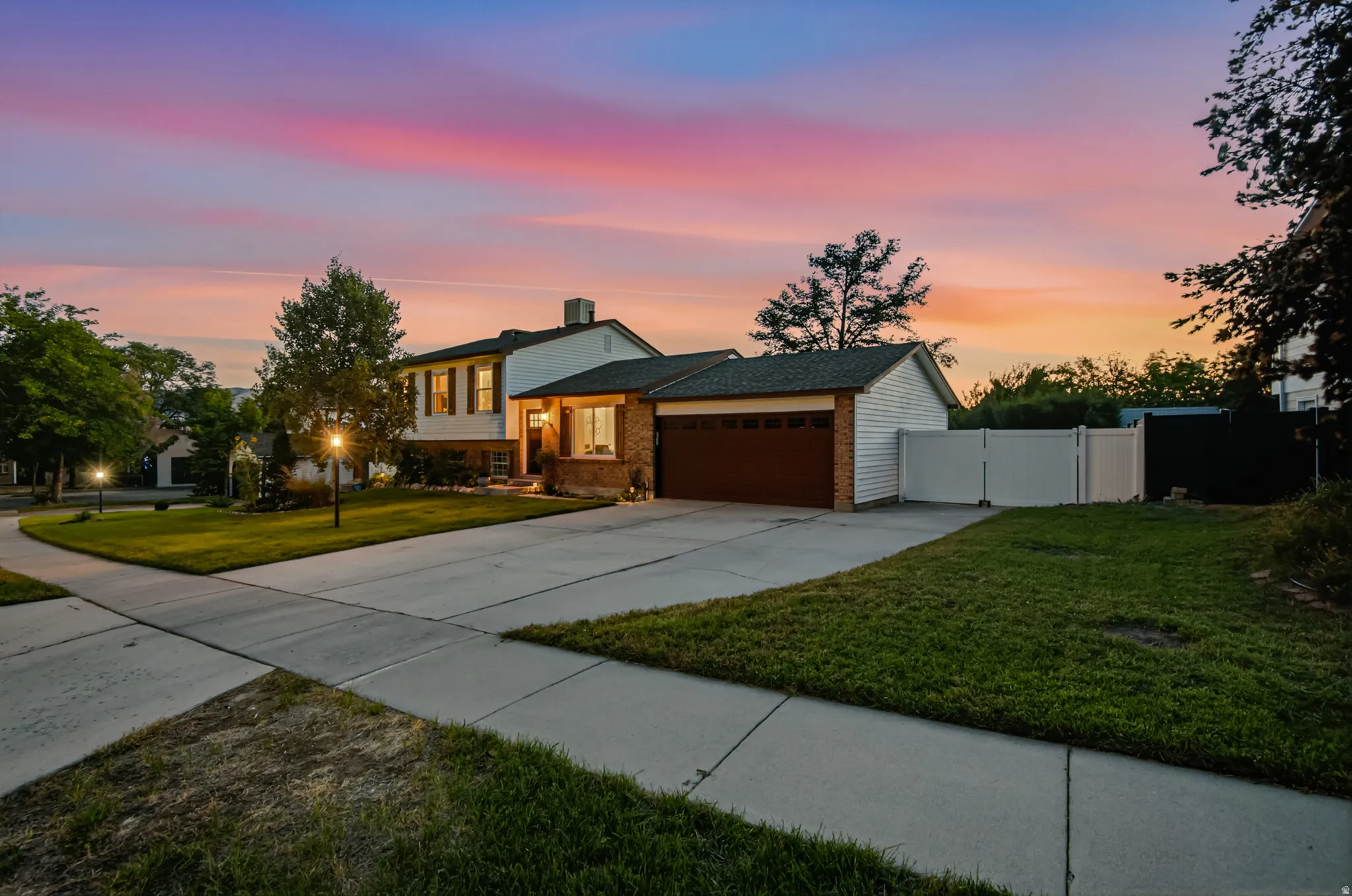 Two-story exterior with a two-car garage, brick facade, and white vinyl siding