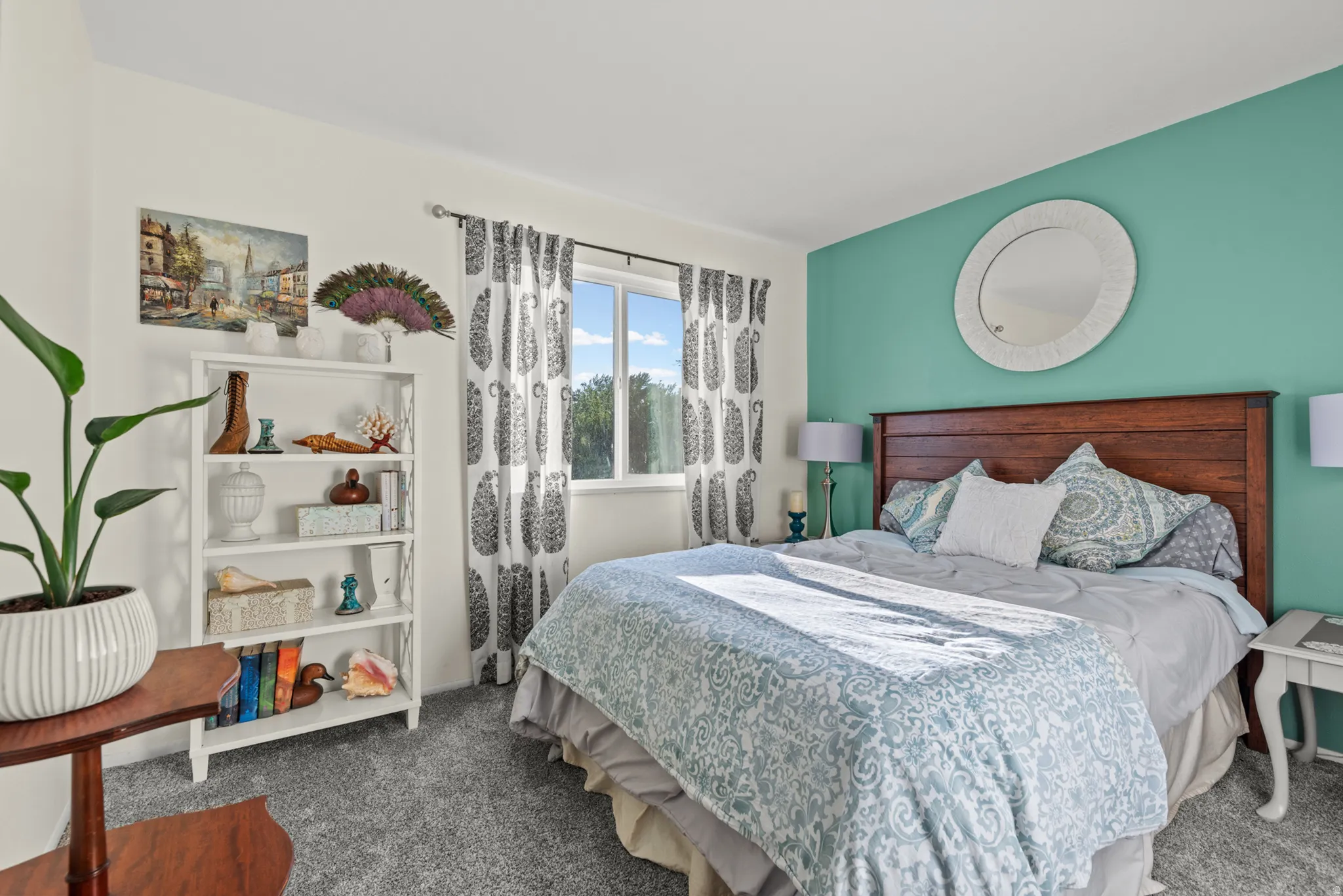 Window offering natural illumination, rich wood-tone headboard, built-in shelving, carpeted flooring, and a decorative wall mirror