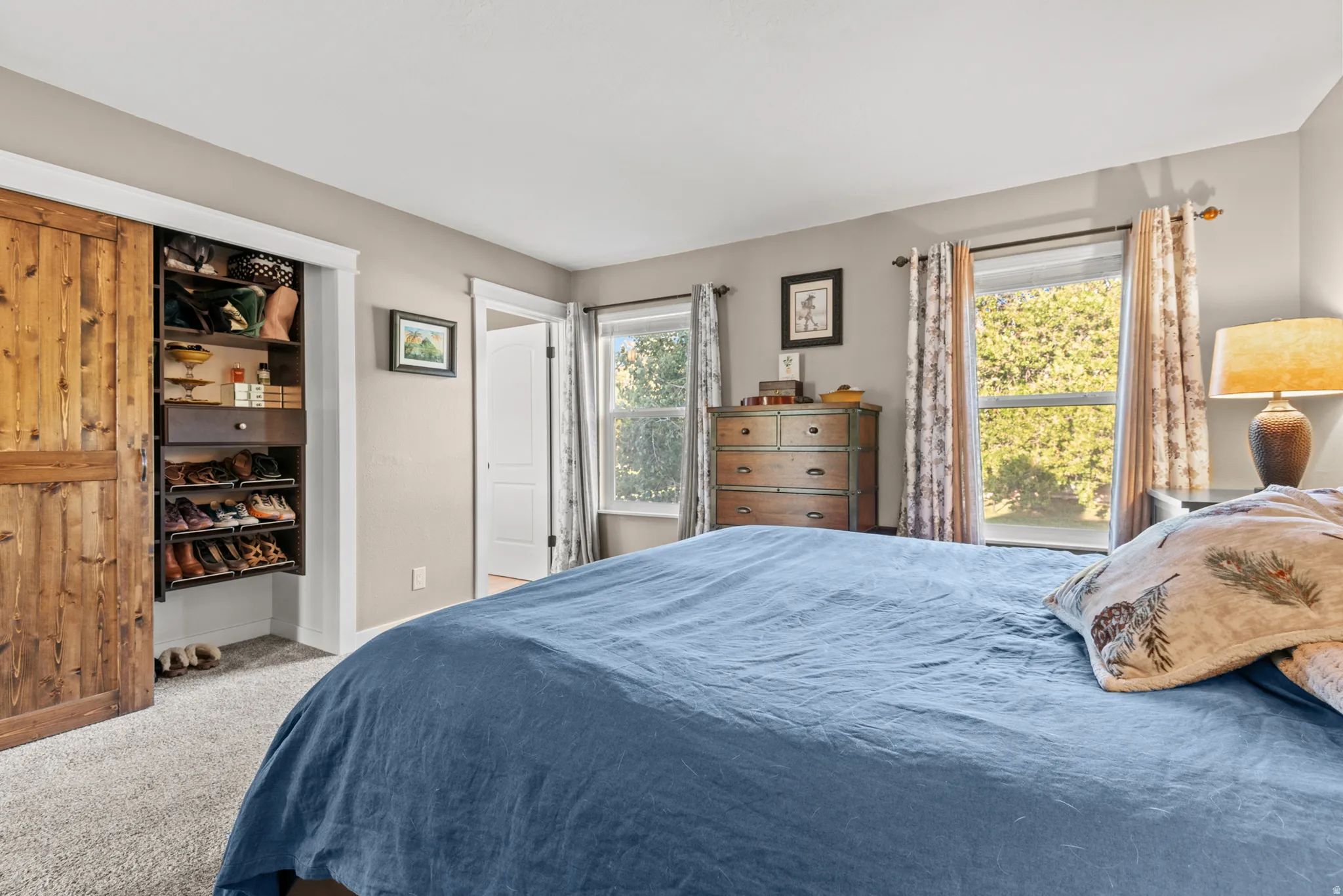 Recessed lighting, wood-finish barn door, built-in closet shelving, dual windows, and light gray wall paint