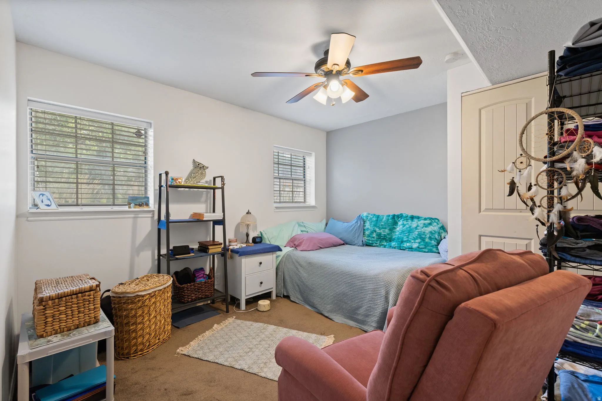 Carpeted room with a ceiling fan light fixture, two windows with horizontal blinds, and a paneled door