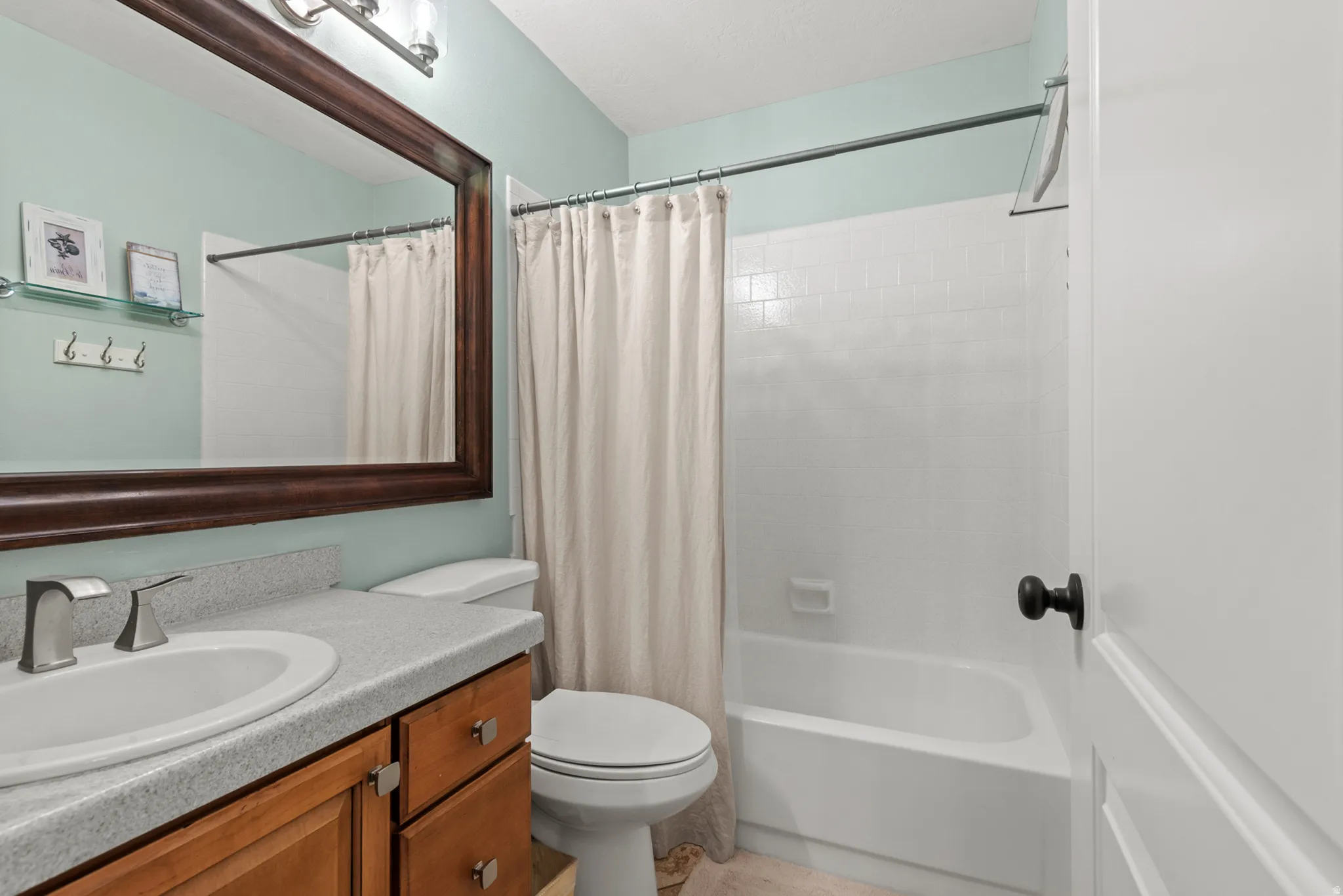 Bathroom featuring a single vanity with a light-toned countertop, wood-finish cabinetry, and a framed mirror