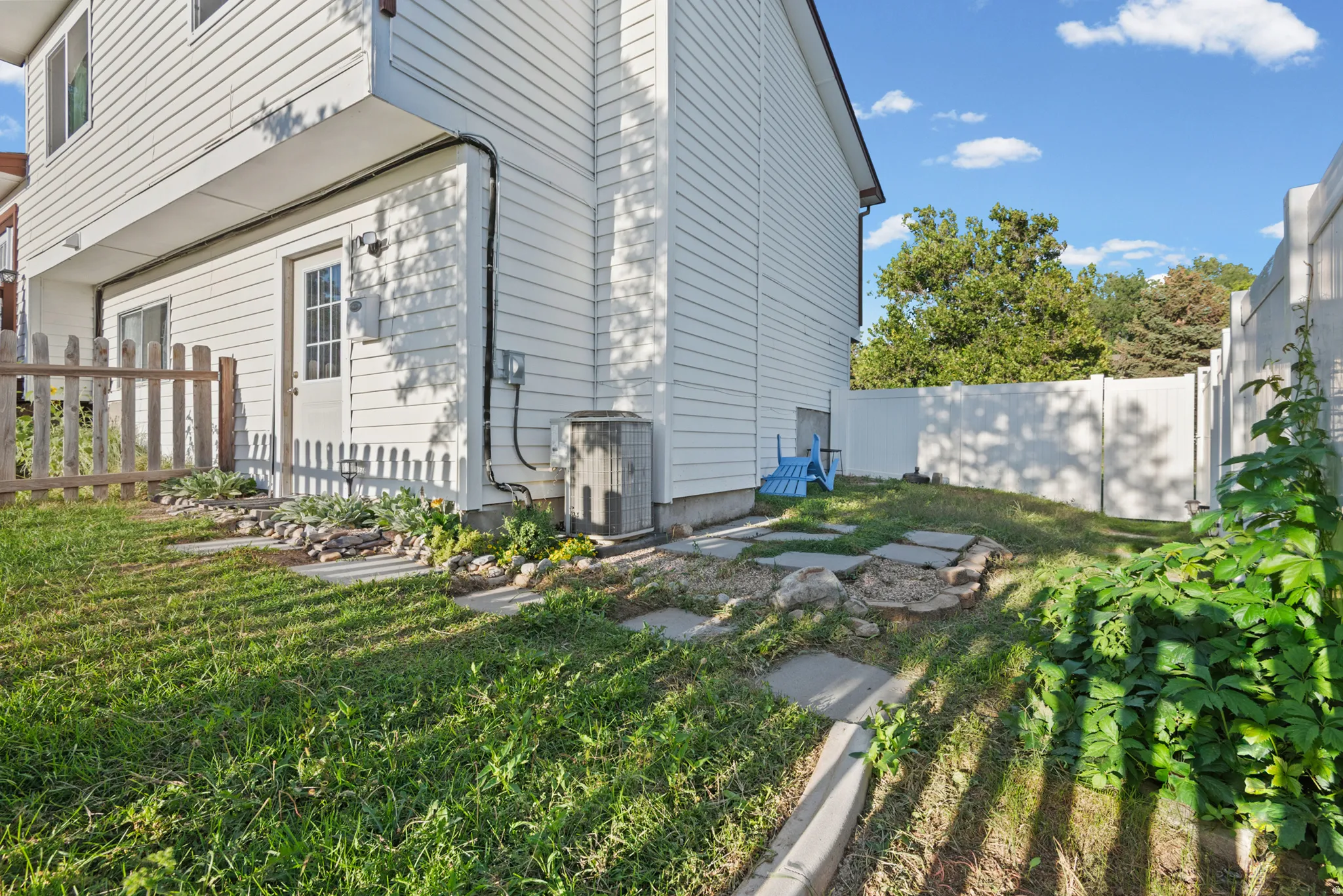 Side yard with white siding, a white privacy fence, and a wooden picket fence