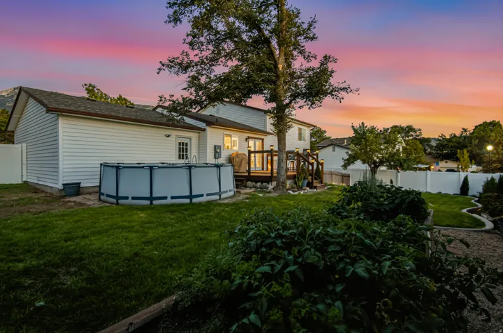 Expansive backyard featuring a manicured lawn, an above-ground pool, a wooden deck, and a privacy fence