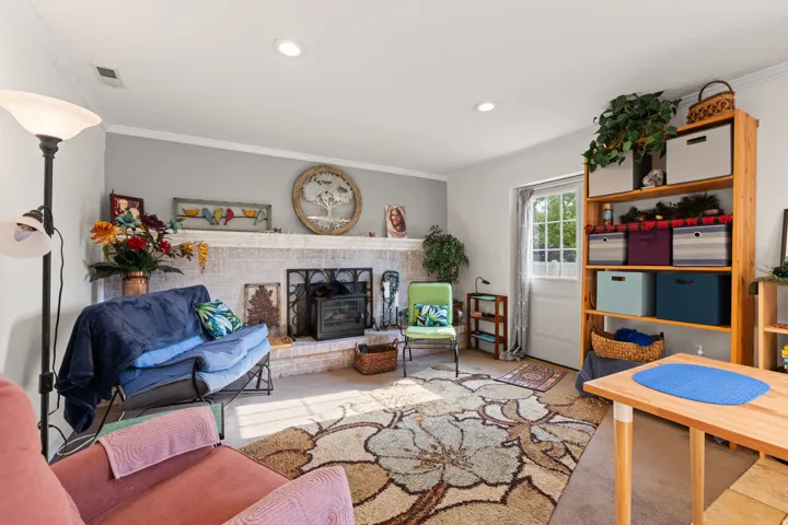 Living area featuring a white-painted brick fireplace with a dark metal firebox insert, recessed ceiling lighting, and crown molding