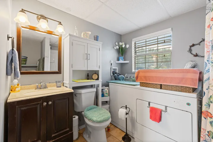 Full bathroom featuring a vanity with a light-toned countertop, a framed mirror, and a three-light fixture