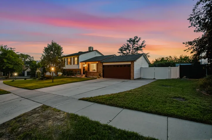 Two-story exterior with a two-car garage, brick facade, and white vinyl siding