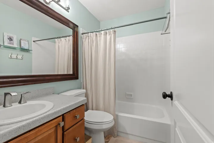 Bathroom featuring a single vanity with a light-toned countertop, wood-finish cabinetry, and a framed mirror