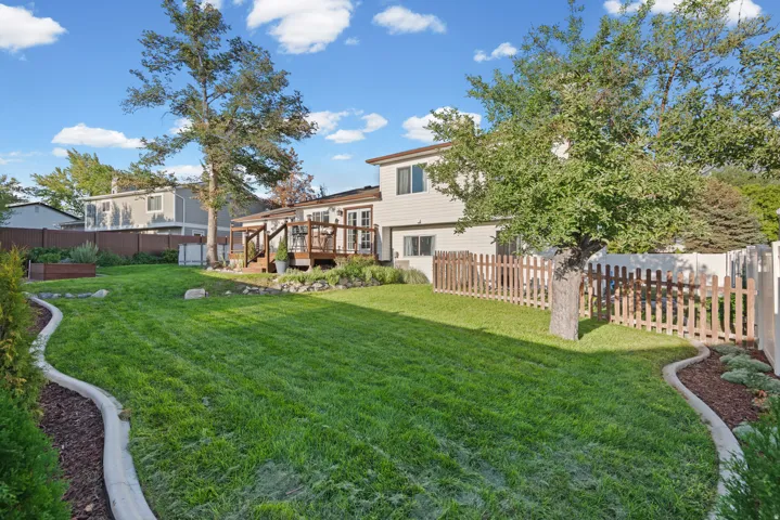Expansive backyard with manicured lawn, mature shade trees, and curved landscape edging