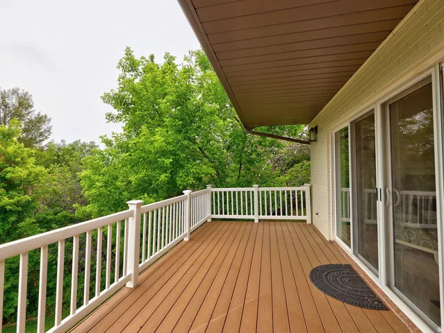 Expansive outdoor deck featuring wood-finish flooring, white railing, and an overhead overhang
