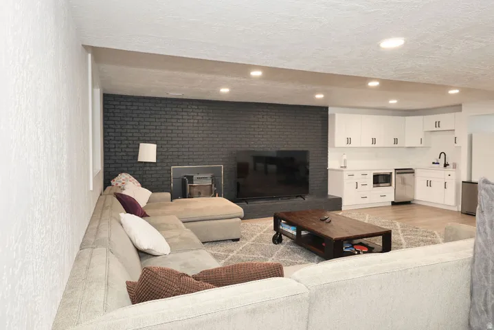 Open recreation area featuring a built-in wet bar, recessed lighting, and a dark brick accent wall with a fireplace
