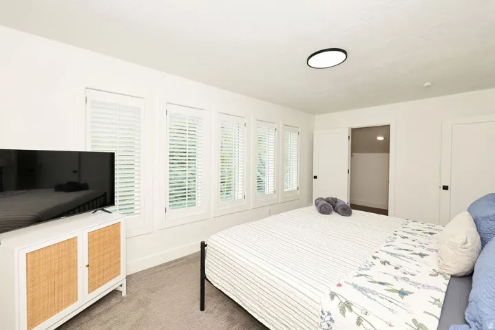 White painted walls with four windows featuring white plantation shutters, a ceiling-mounted light fixture, and two white interior doors