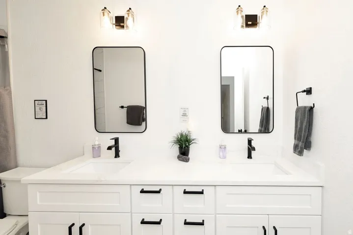 Double vanity featuring white shaker-style cabinetry, integrated rectangular sinks, and matte black hardware