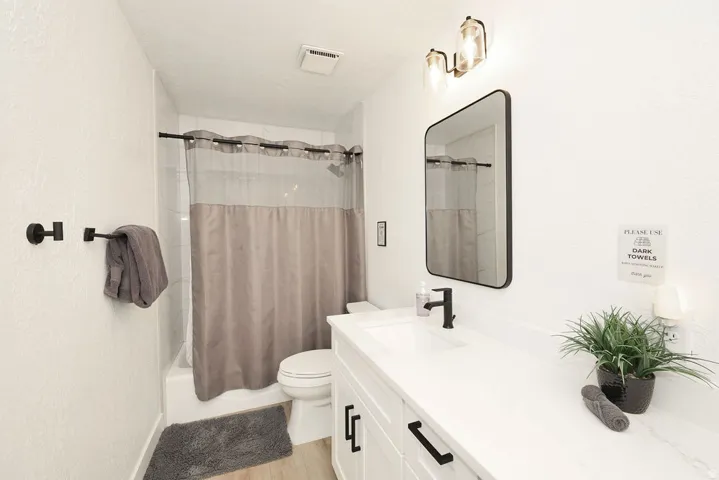Contemporary bathroom featuring a white vanity with a single basin, black hardware, and an overhead vanity light