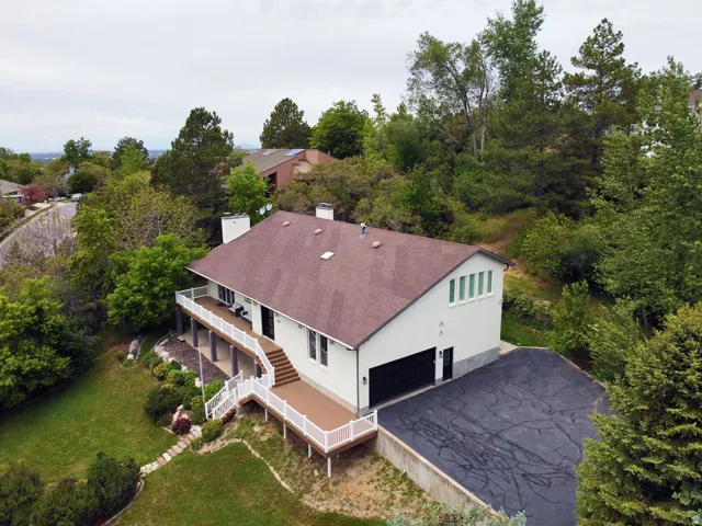Two-story residence featuring a large wrap-around deck, integrated two-car garage, and a spacious paved driveway