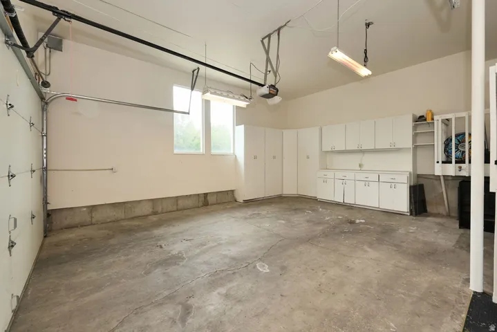 Spacious garage featuring a concrete floor, built-in white cabinetry, and multiple windows