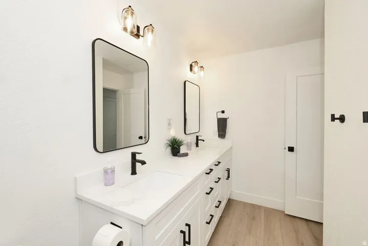 Dual vanity with white cabinetry and integrated sinks, complemented by matte black hardware and faucets
