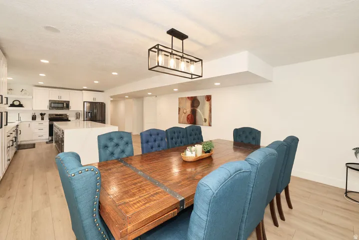 Open-concept living space featuring wood-finish flooring, recessed lighting, and a modern rectangular chandelier