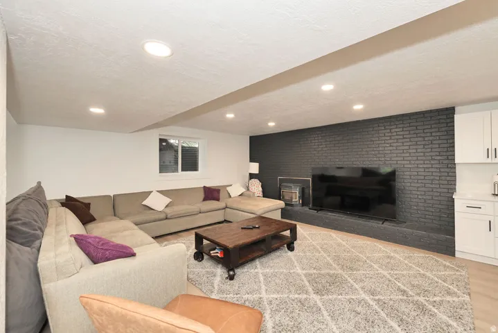 Finished living space featuring a dark brick accent wall, recessed lighting, and light wood-finish flooring