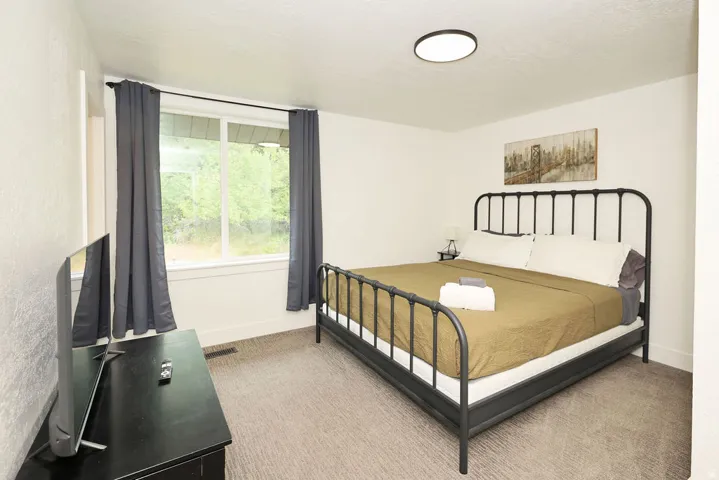 Bedroom featuring a window with exterior tree scenery, carpeted flooring, a flush-mount ceiling light, and white painted walls