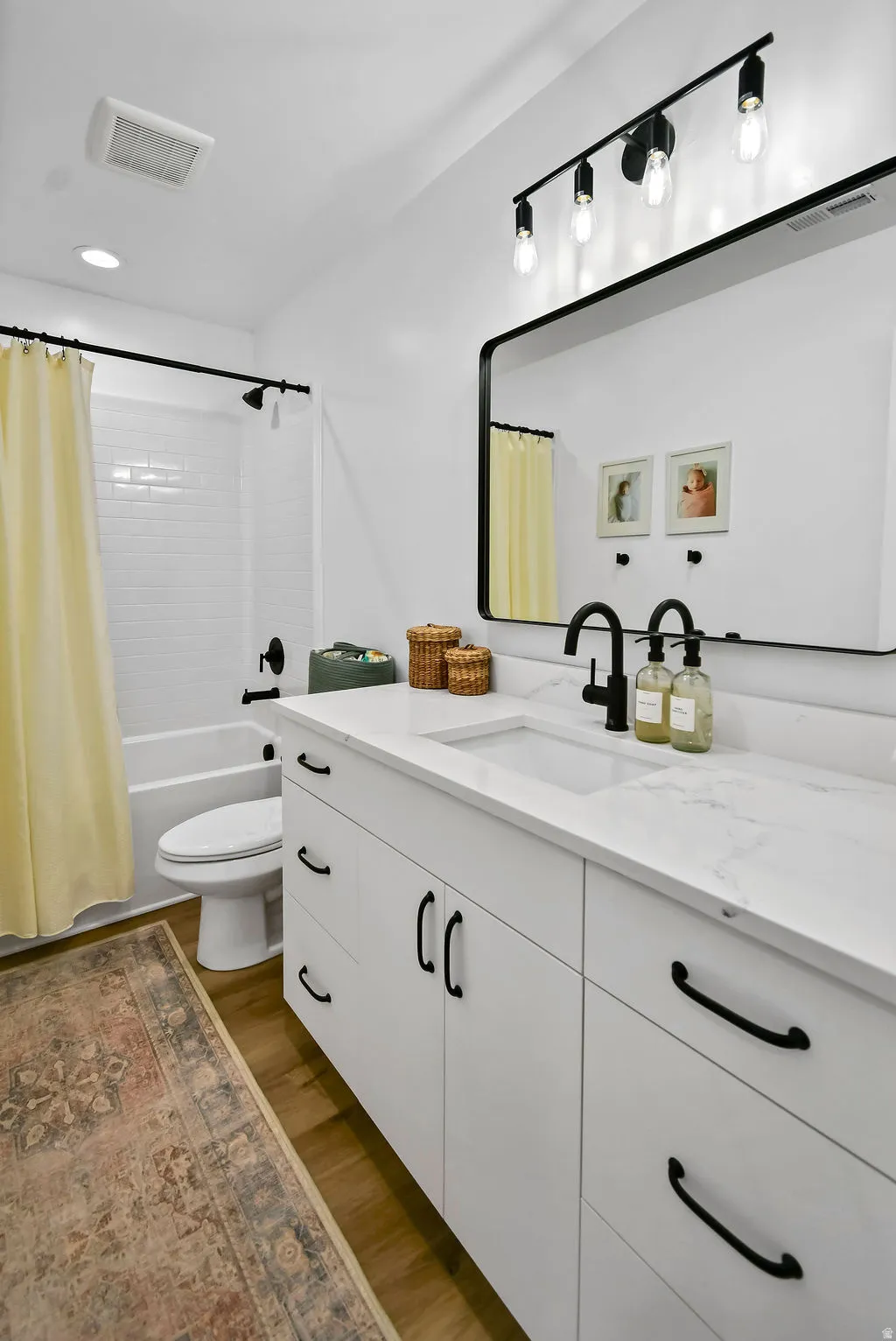 Modern bathroom featuring a white vanity with black hardware, an integrated rectangular sink, and a contrasting black framed mirror