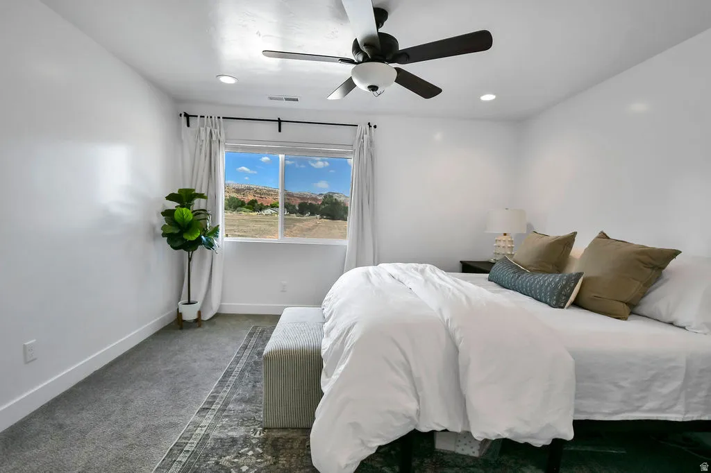 Carpeted room featuring a ceiling fan with integrated lighting, recessed lighting, and a window with white trim