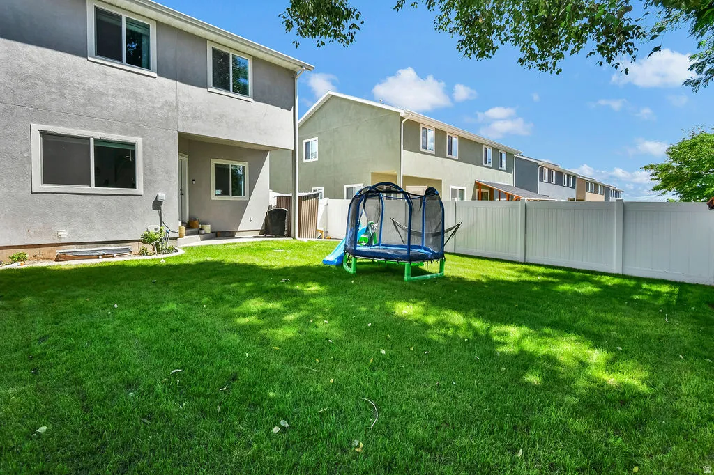 Expansive green lawn providing outdoor space, bordered by a white privacy fence
