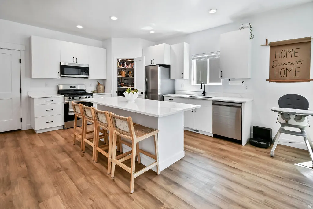 Bright kitchen featuring white cabinetry and wood-finish flooring