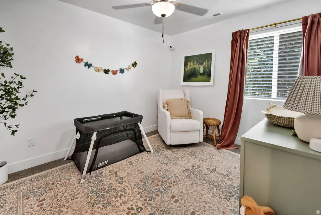 Bedroom featuring a ceiling fan, white walls, and wood-finish flooring with an area rug