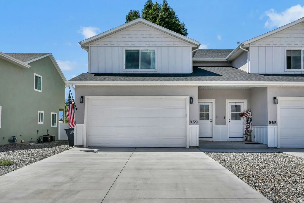Two-story townhouse exterior with a light stucco finish and white board-and-batten siding