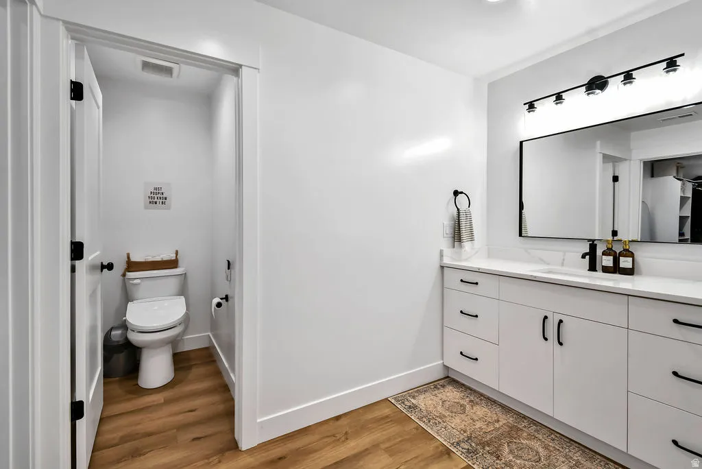 Modern bathroom featuring a white vanity with extensive storage, a single integrated sink, and a black-framed mirror with multi-bulb lighting