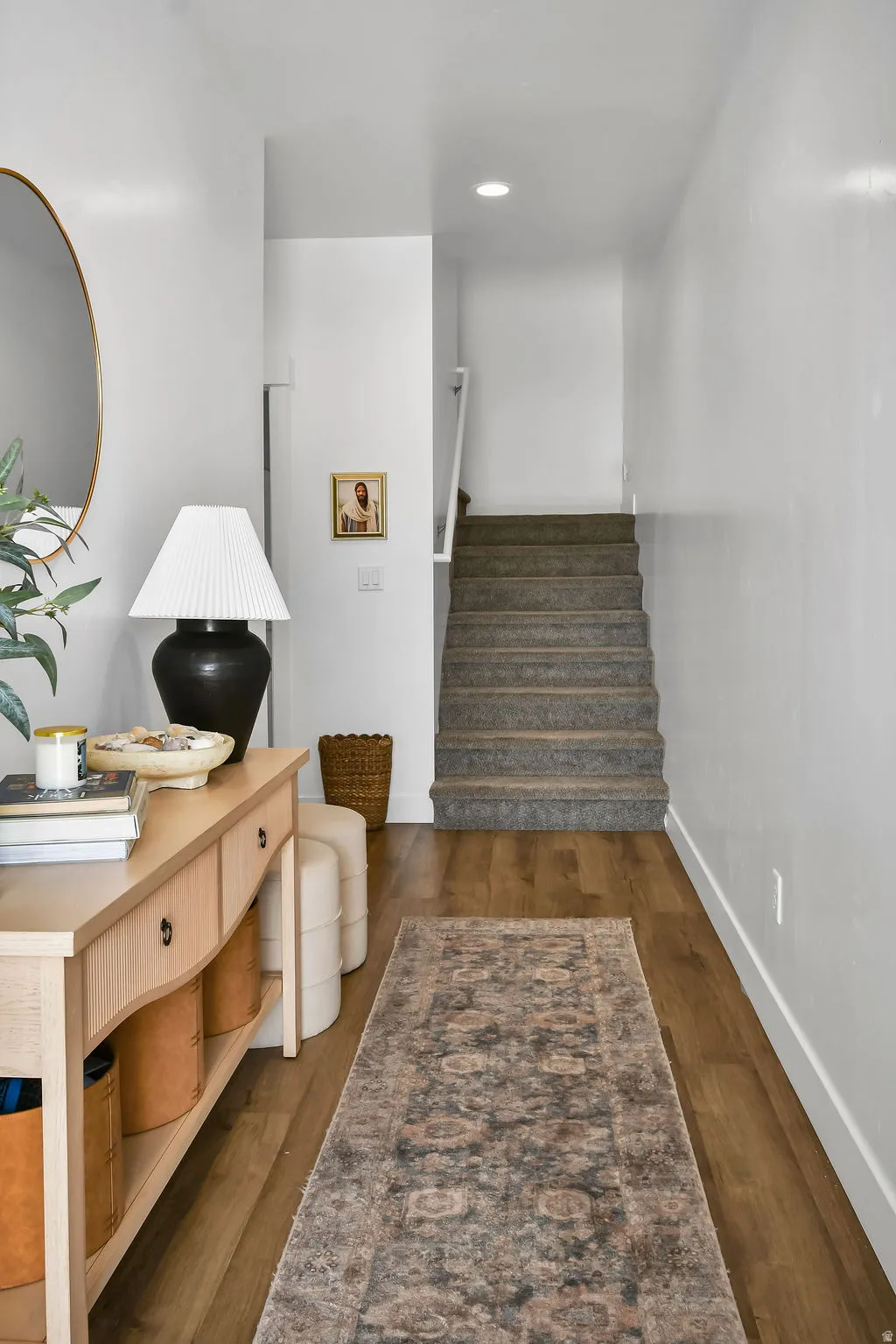 Entryway featuring wood-finish flooring, white walls, and a carpeted staircase