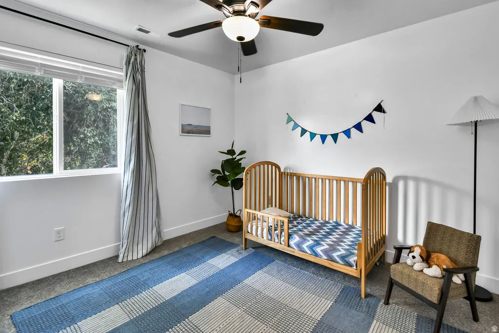 Bright room with a large window, a ceiling fan, and carpeted flooring
